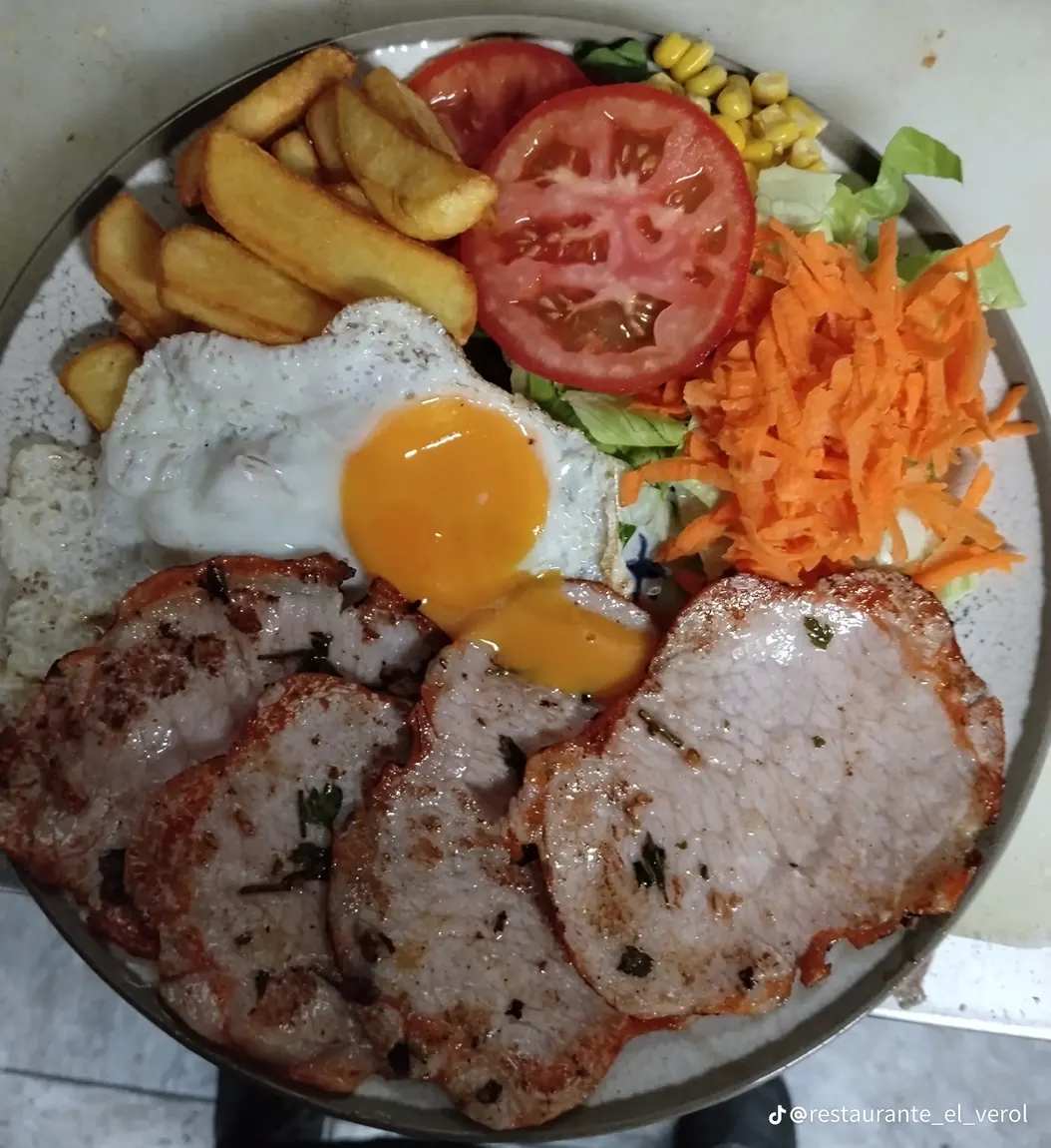 Plato con pata asada, huevo frito, papas y ensalada